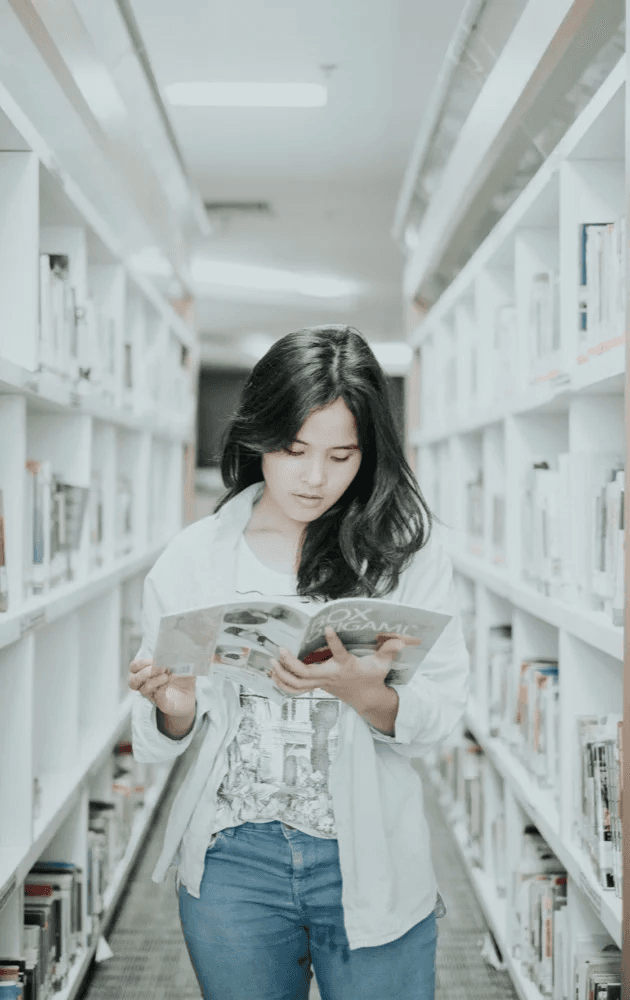 Femme dans une bibliothèque lisant un livre